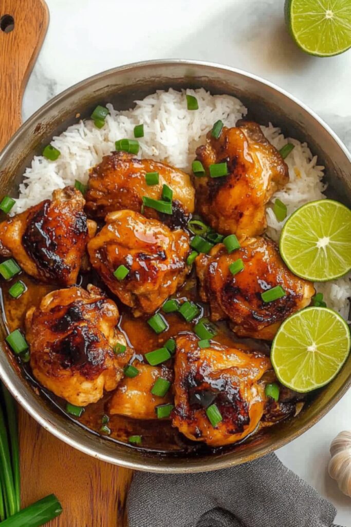 Glazed chipotle honey chicken thighs served over rice with lime slices and green onion garnish