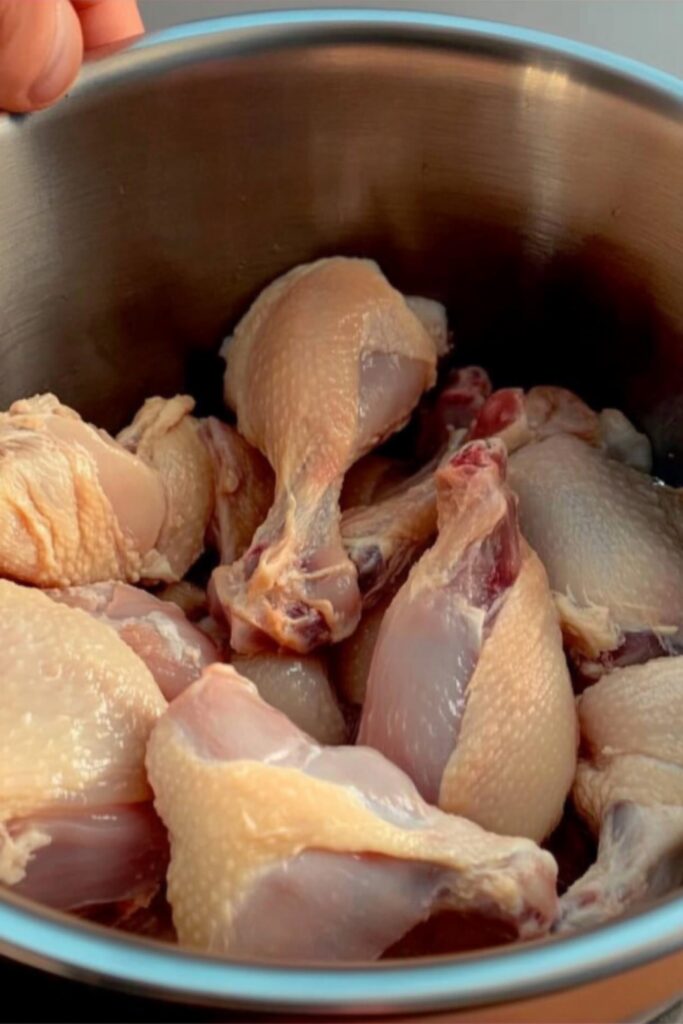 Raw chicken drumsticks in a metal bowl, ready for brining.