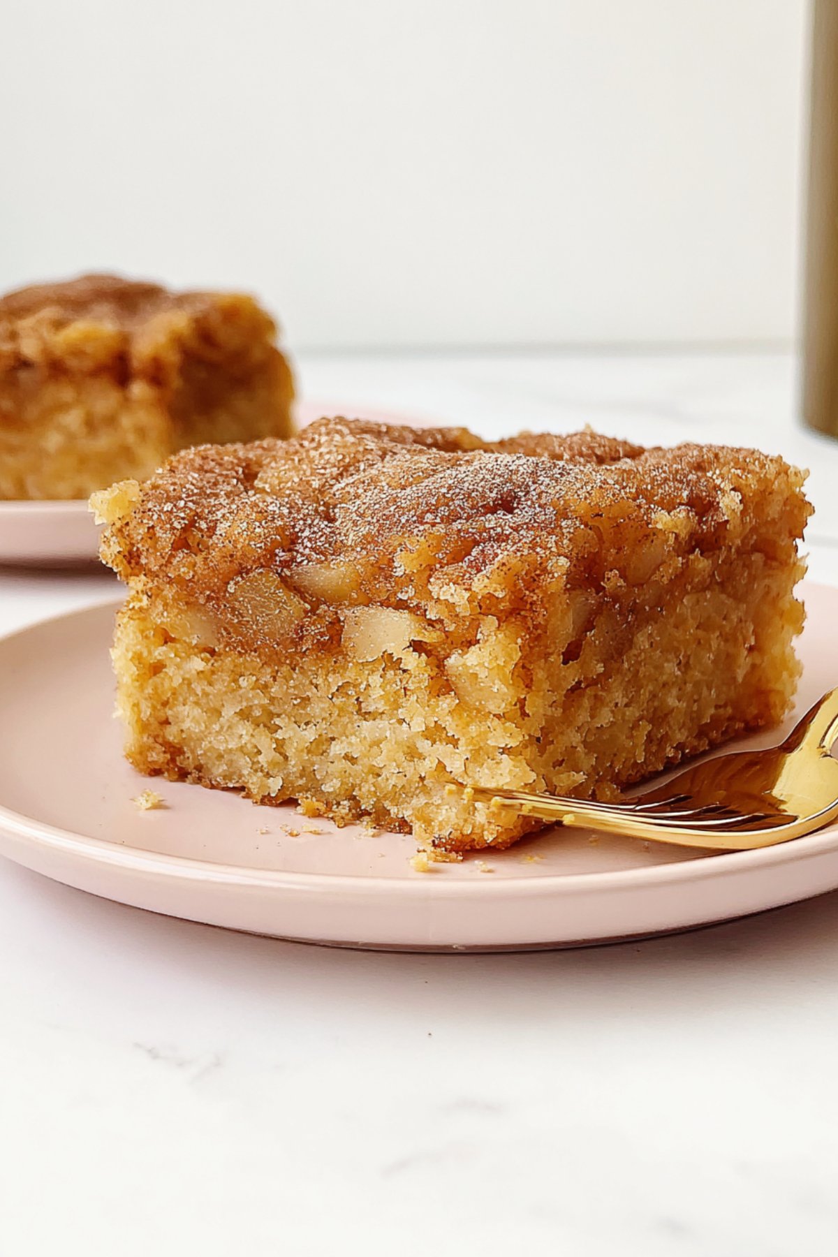 Close-up of apple snack cake square showing moist apple chunks and cinnamon topping.