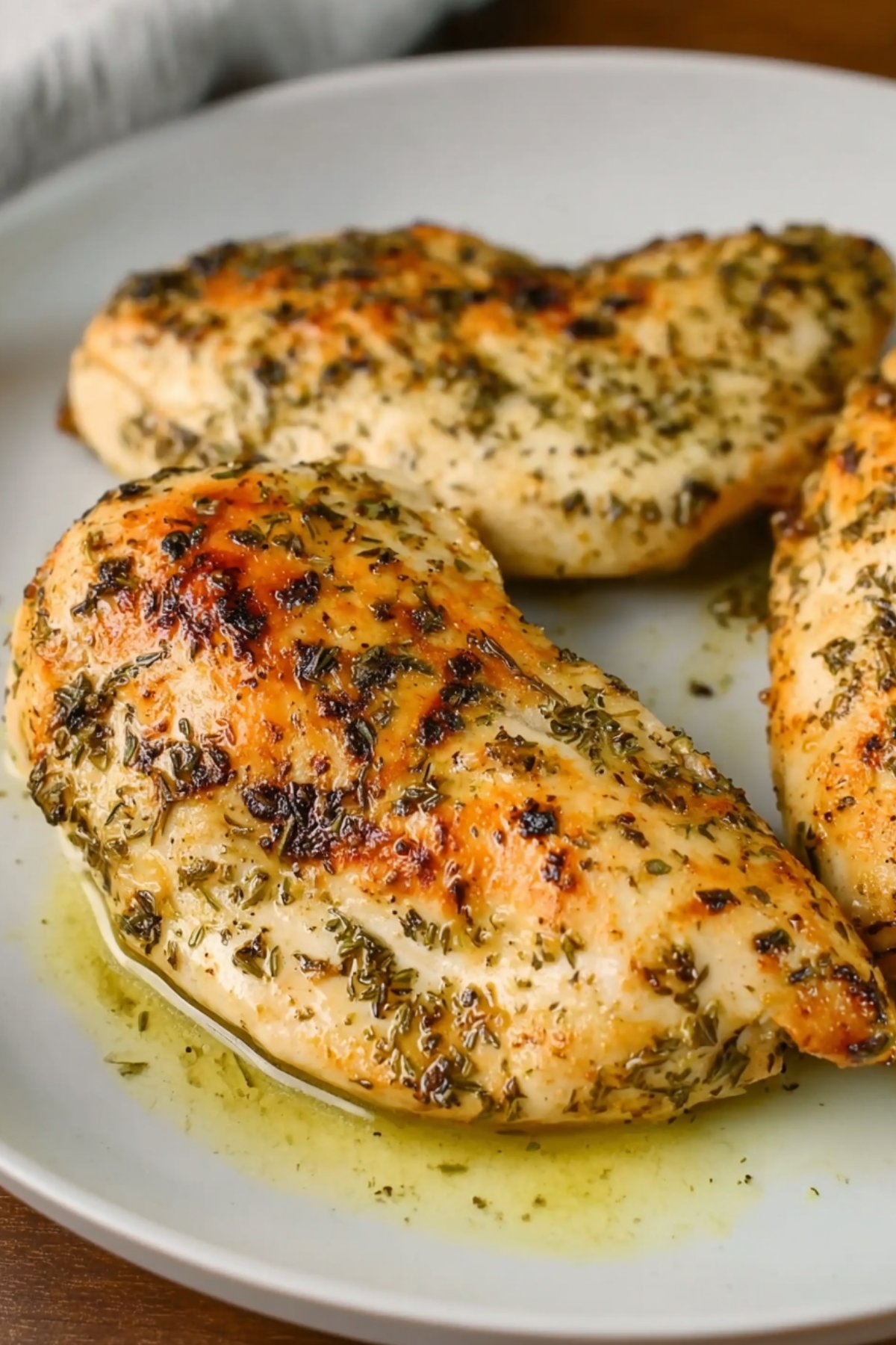 Golden brown chicken breasts cooked with herbs and olive oil on a plate, perfect for a quick chicken breast dinner.