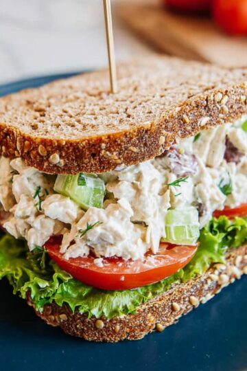 Close-up of traditional chicken salad sandwich with lettuce, tomato, and seeded bread.