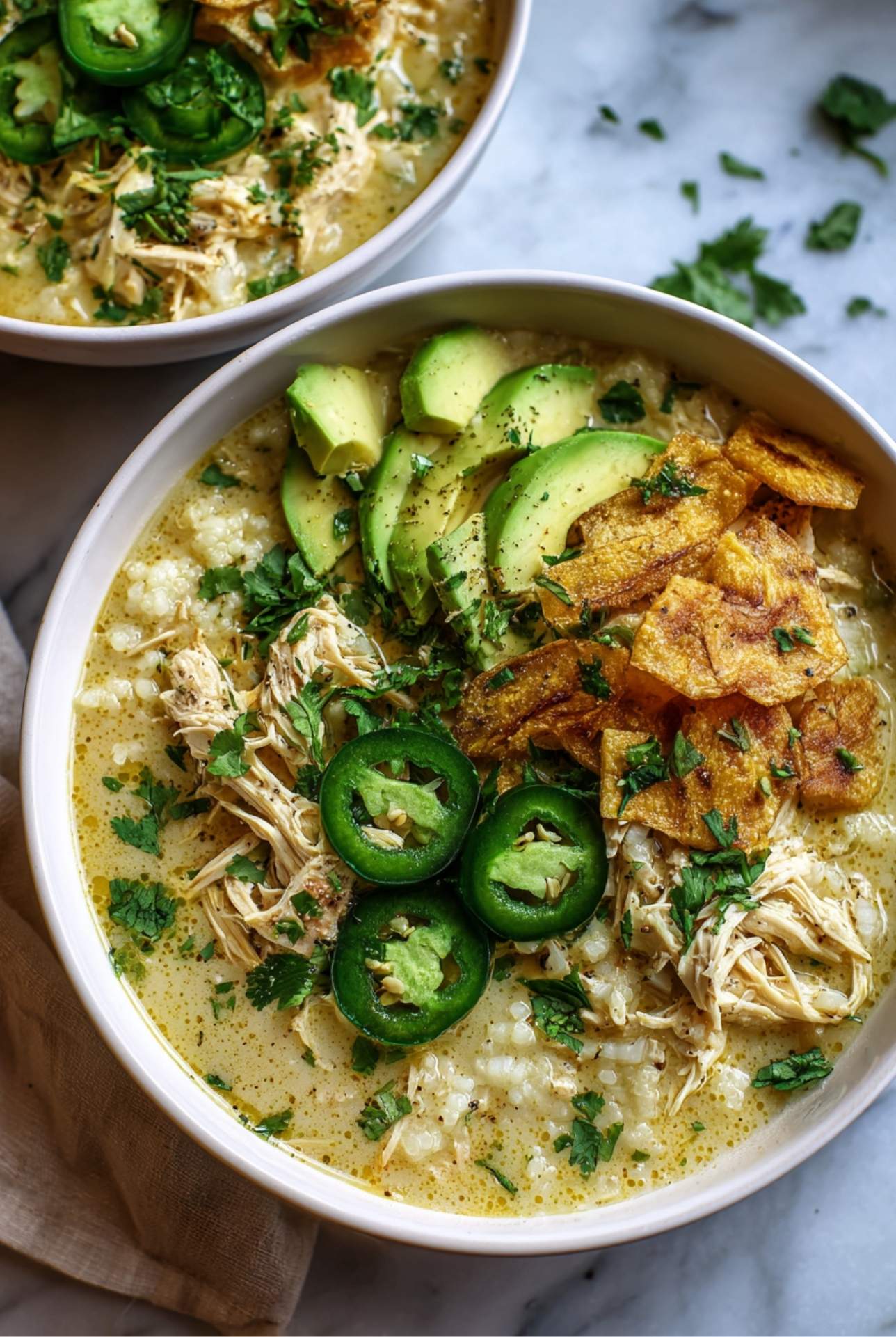Whole30 white chicken chili topped with avocado, plantain fries, jalapeño, and cilantro.