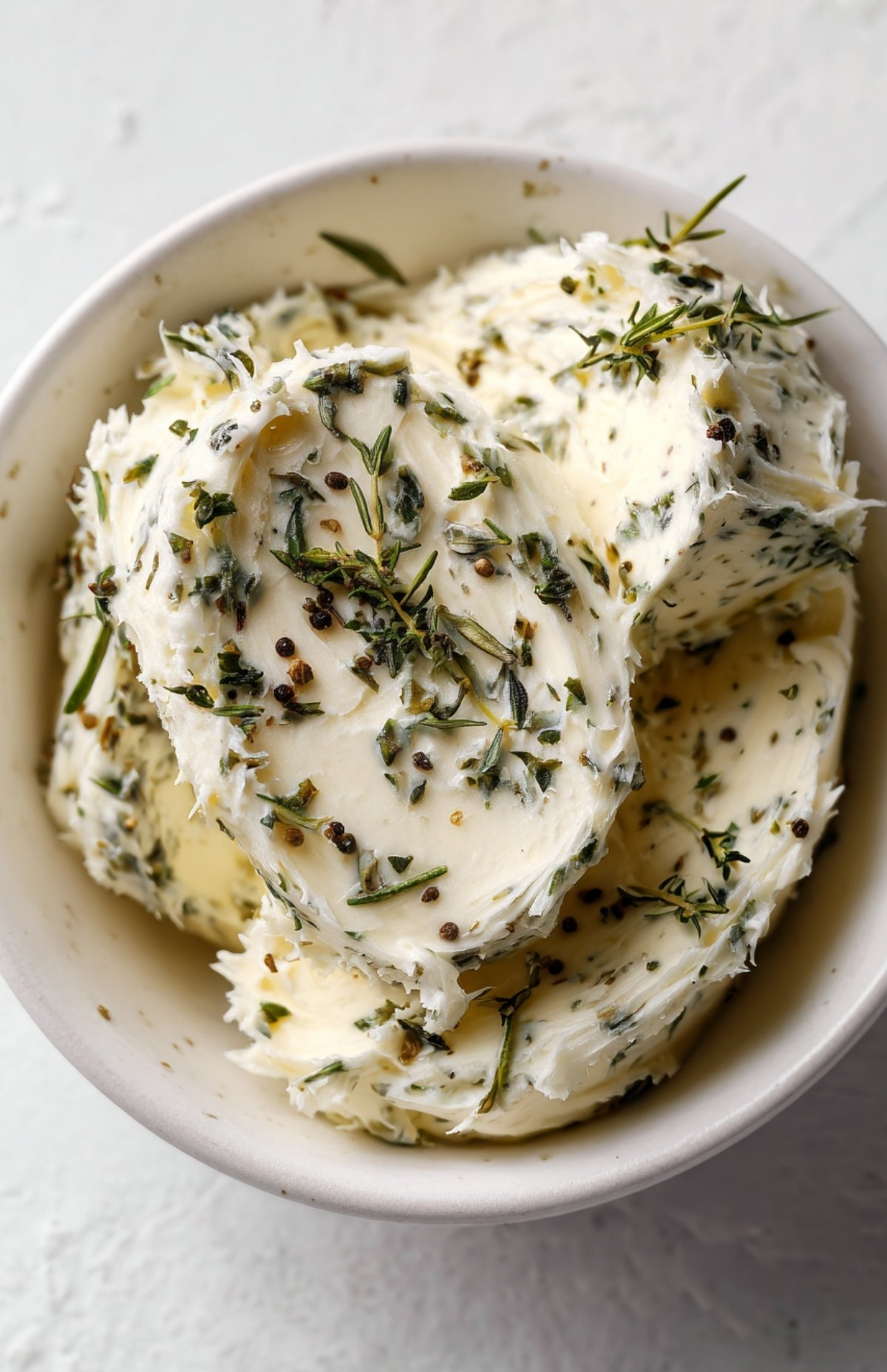Bowl of homemade garlic herb butter with rosemary and thyme.