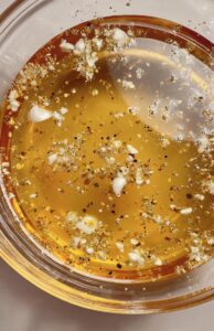 Raw turkey breast-side down in a clear container filled with garlic, pepper, and salt brine.