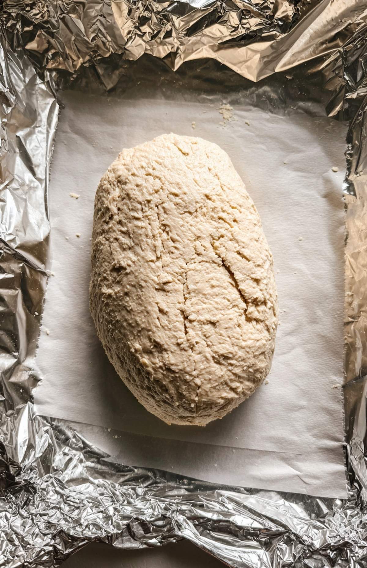 Shaped vegan turkey loaf on parchment and foil, ready to steam before roasting.
