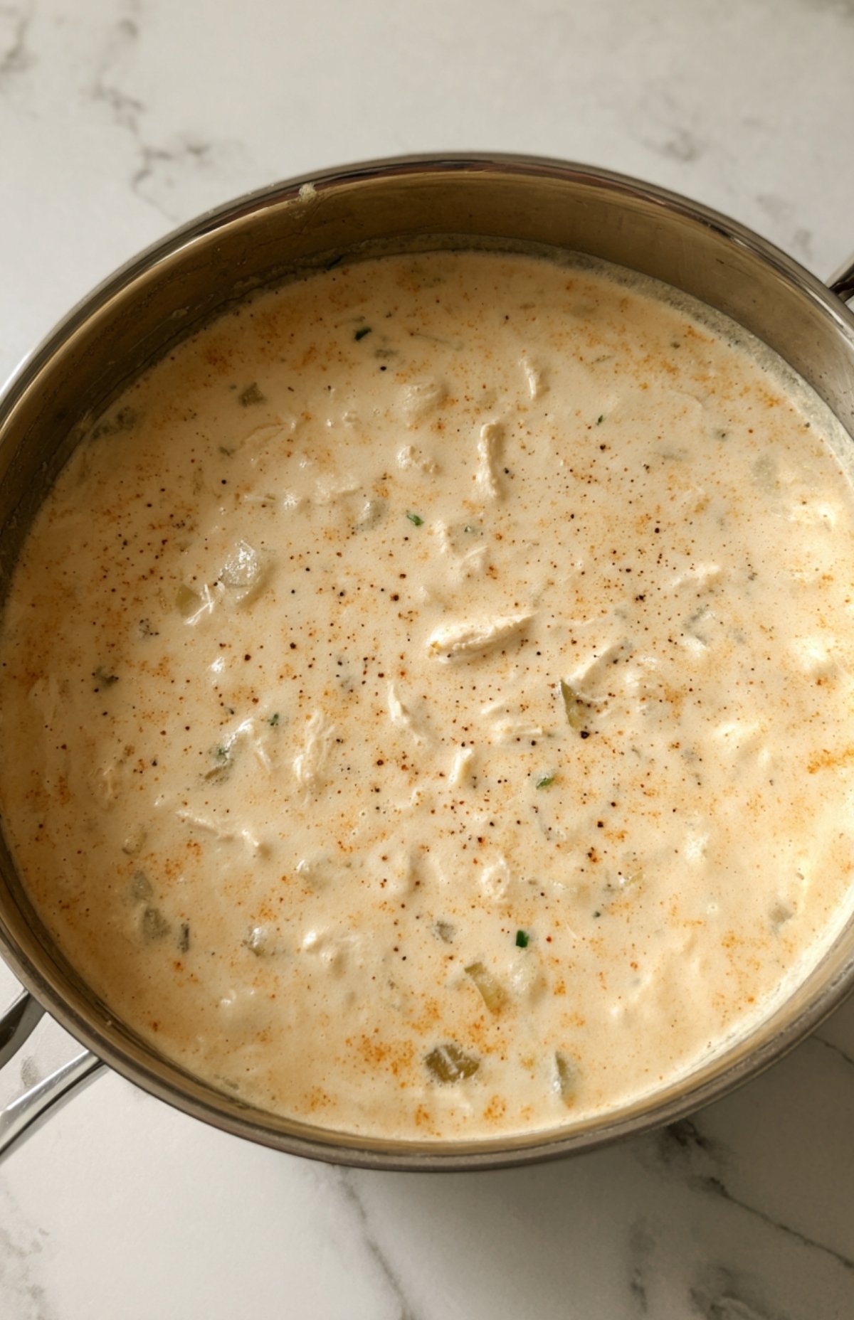 Pot of creamy white bean chicken chili with smooth broth and tender chicken pieces.