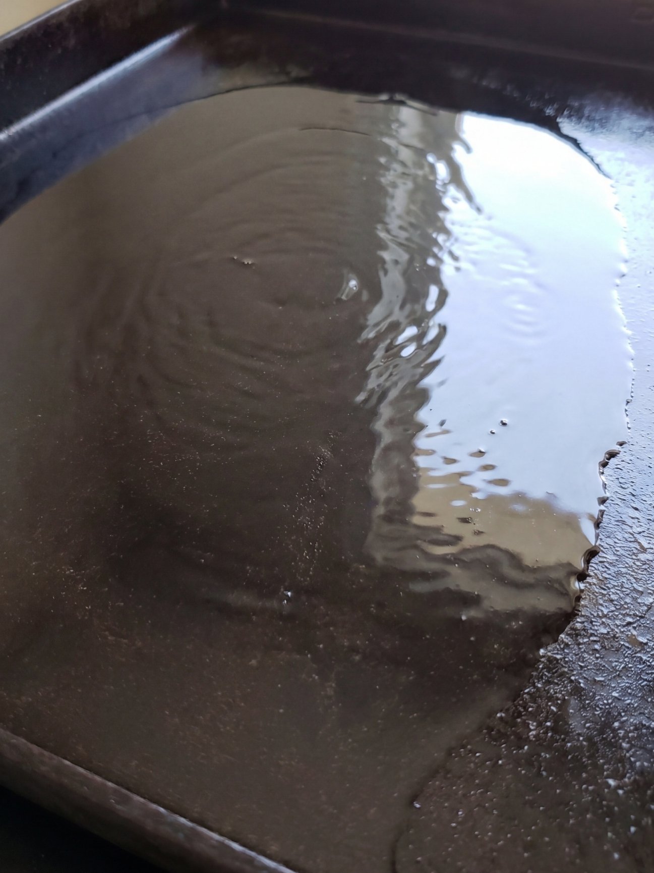 Close-up of a preheated Blackstone griddle surface shimmering with a thin layer of cooking oil.